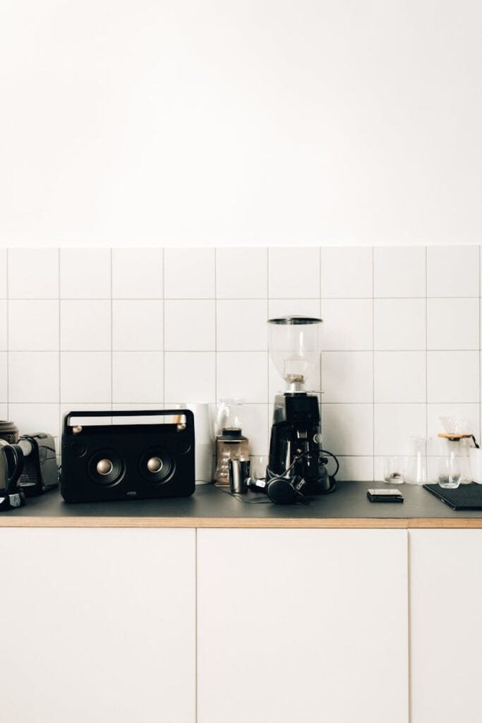 a coffee maker beside black speaker on kitchen table top