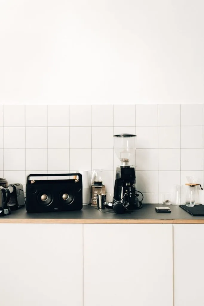 a coffee maker beside black speaker on kitchen table top