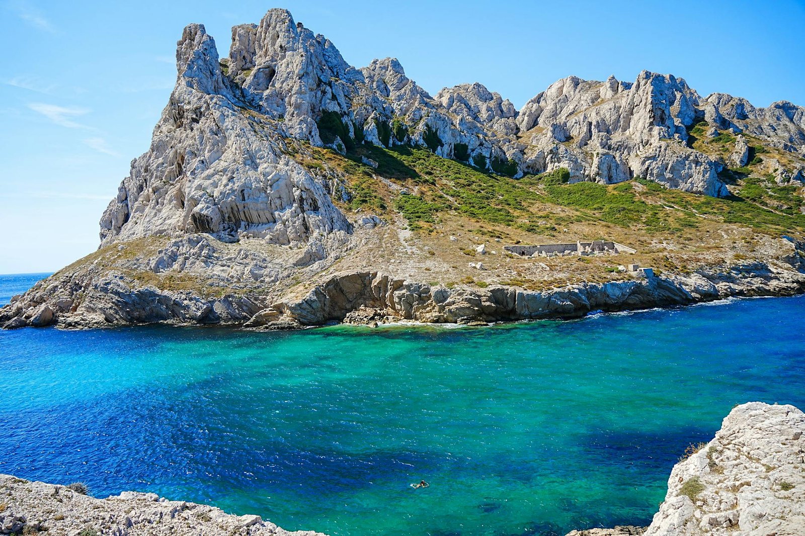a rocky shoreline with blue water and green rocks